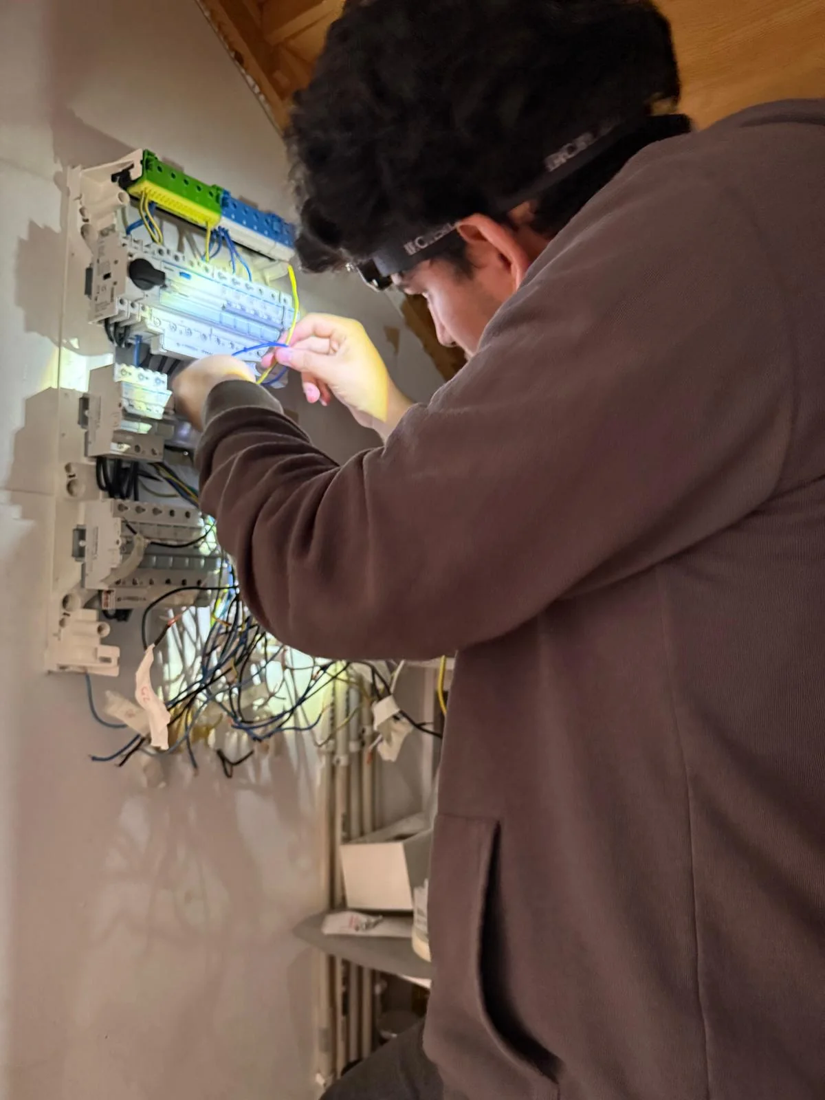 Elektriker med pannlampa felsöker i en elcentral